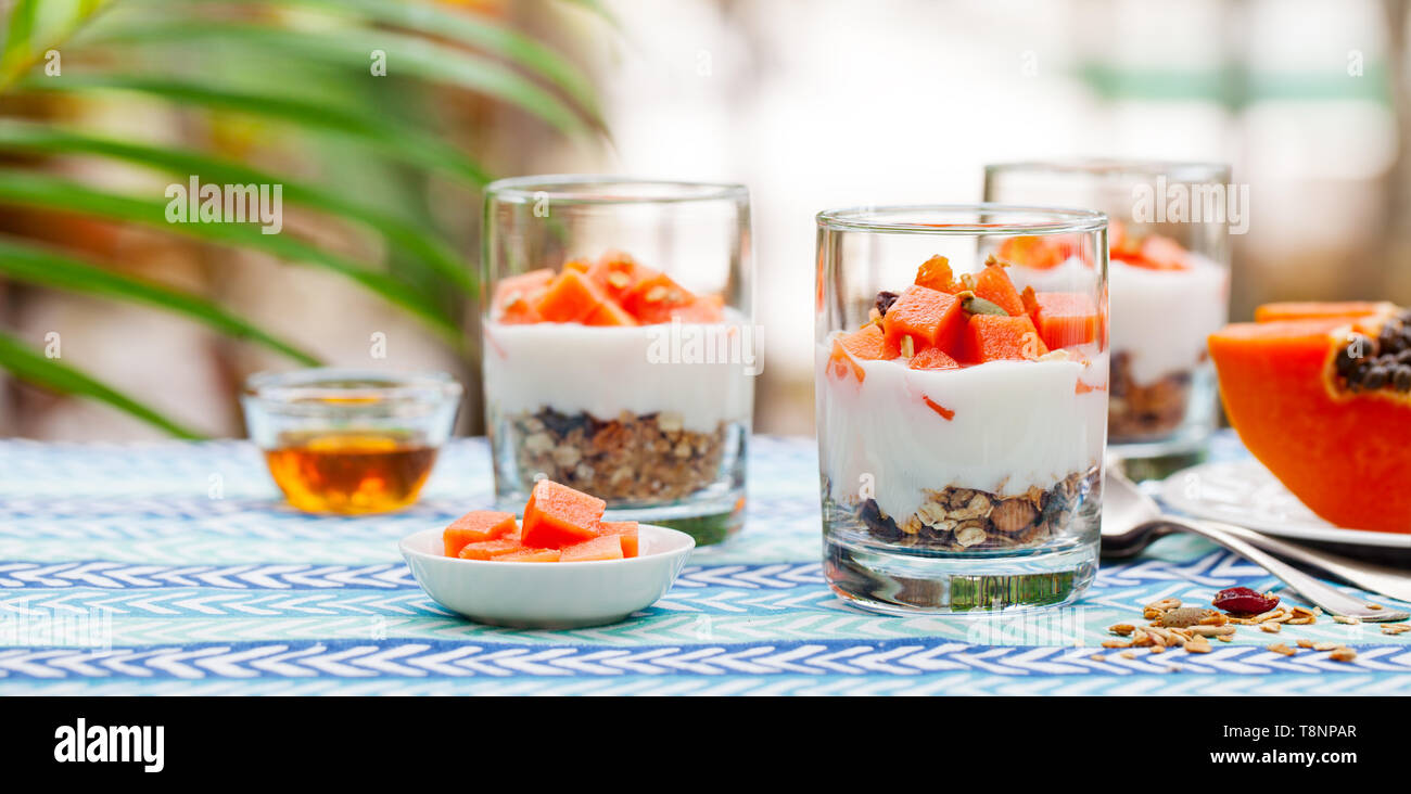 Il dessert con papaia, yogurt e granola in bicchieri. Sfondo all'aperto. Foto Stock