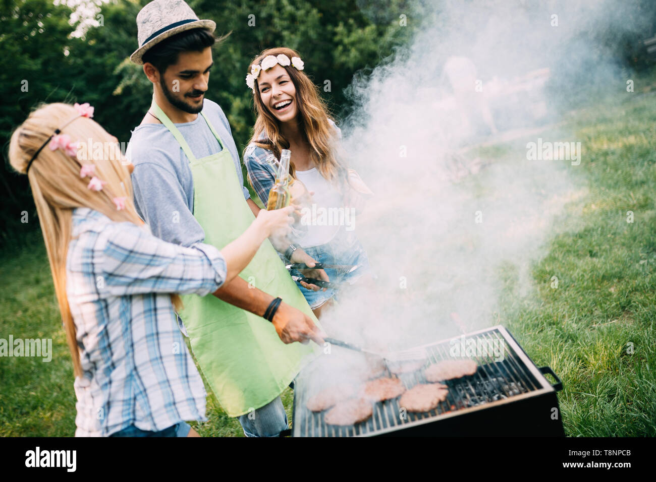 Gruppo di amici felice avente il barbecue nella foresta Foto Stock