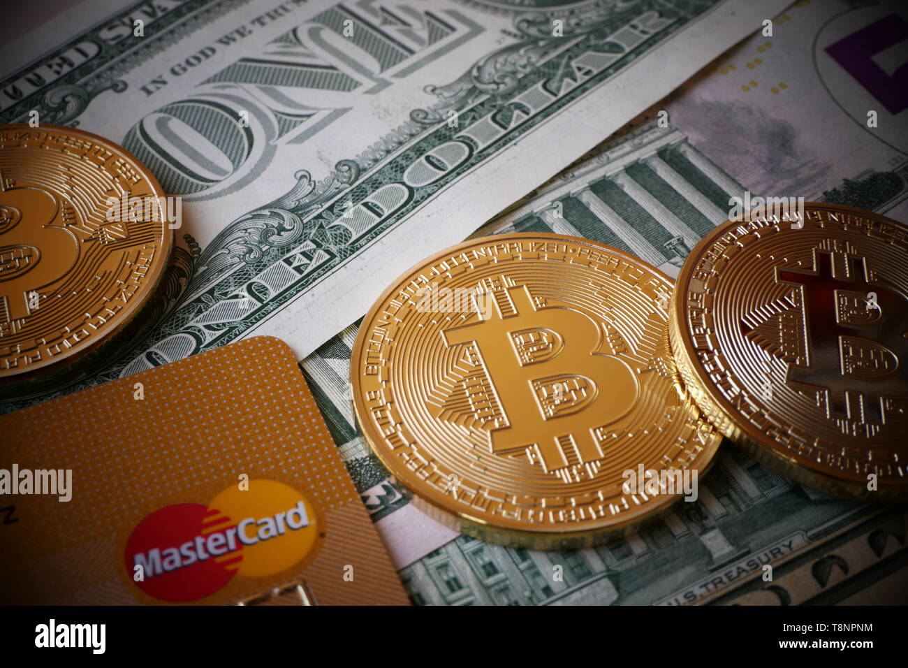 Berlino, Germania - 1 dicembre 2018: Bitcoins, una moneta virtuale in forma fisica, visualizzato su di Dollari Usa note e una carta di credito MasterCard Foto Stock