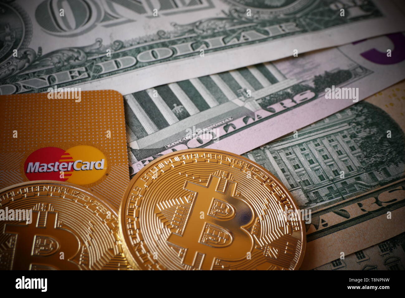 Berlino, Germania - 1 dicembre 2018: Bitcoins, una moneta virtuale in forma fisica, visualizzato su di Dollari Usa note e una carta di credito MasterCard Foto Stock