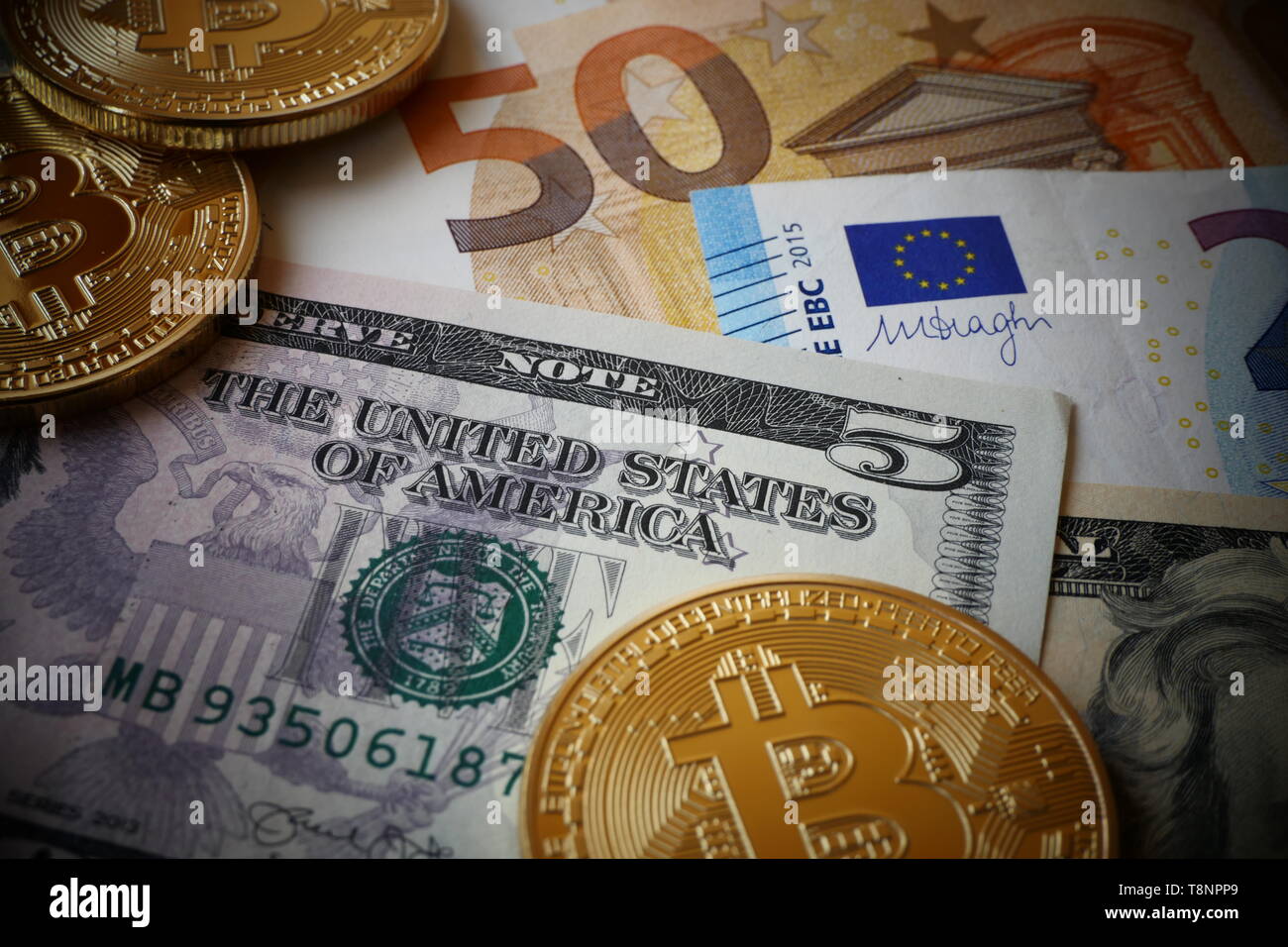 Bitcoins, una moneta virtuale in forma fisica, visualizzato sul dollaro Usa e le banconote in euro Foto Stock