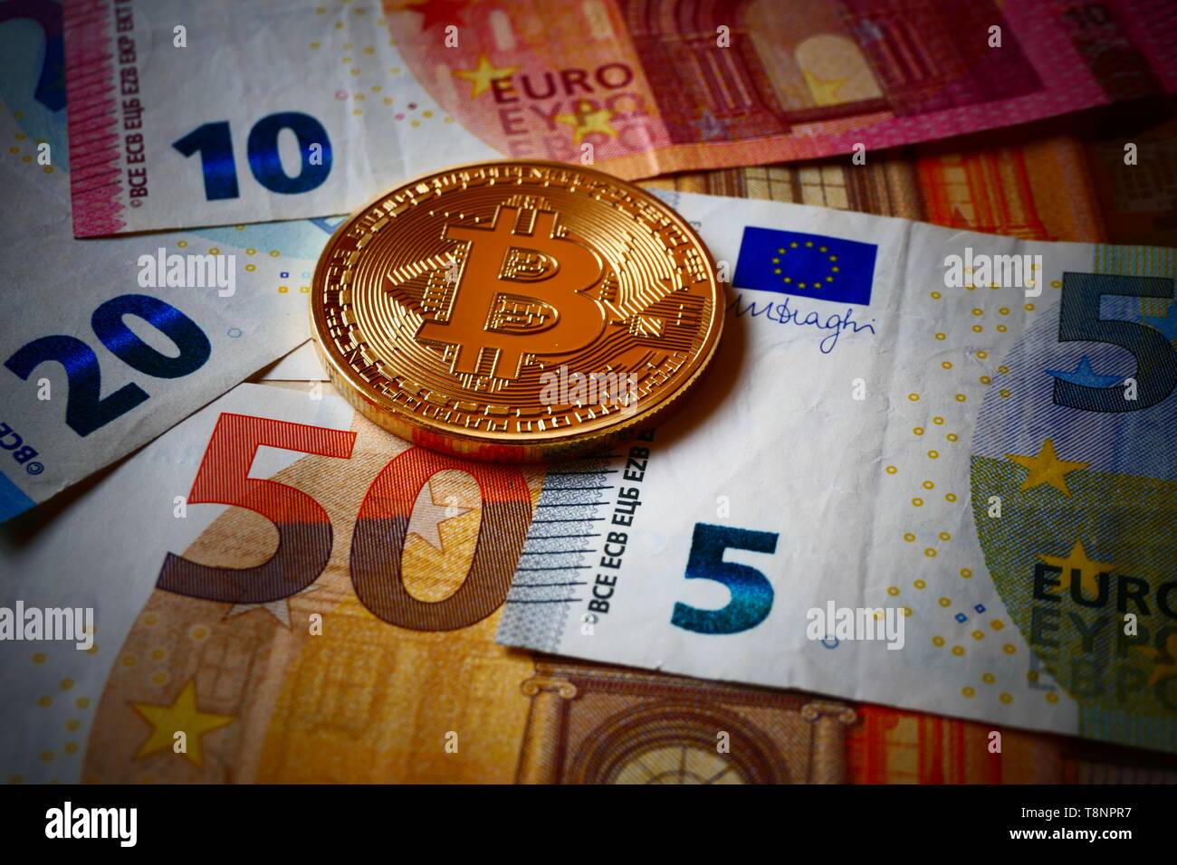 Un golden Bitcoin, una moneta virtuale in moneta fisica form visualizzato sulle banconote in euro Foto Stock