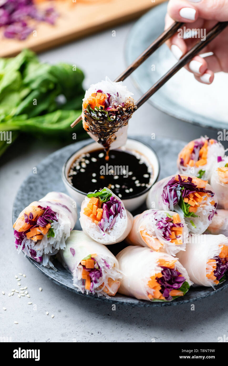 Carta in rotoli di riso o molla freschi panini farciti con verdure e gamberi. Persona di mangiare panini, cucina asiatica Foto Stock