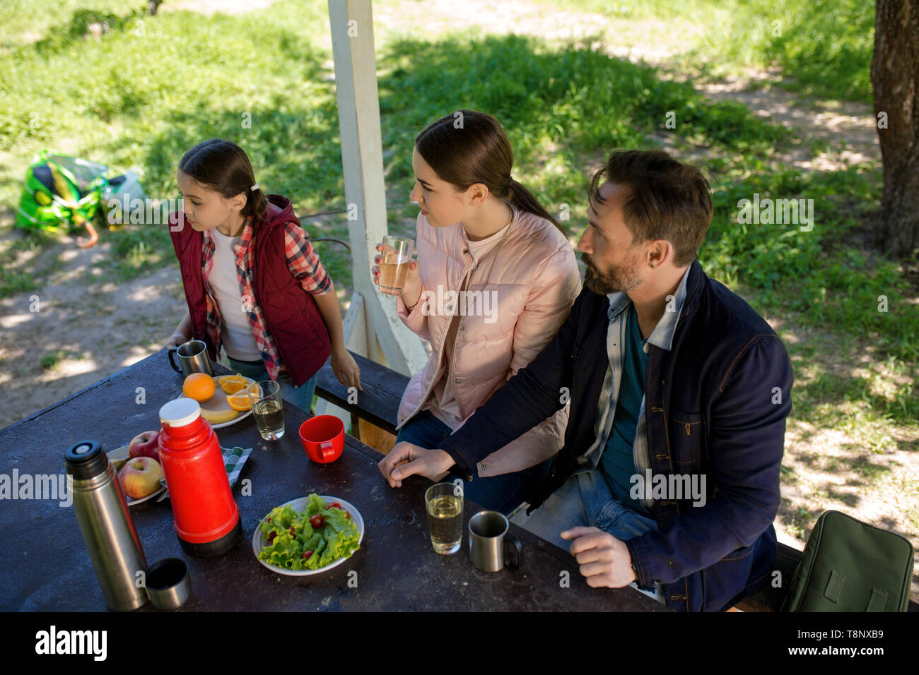 Famiglia sono seduti a tavola in gazebo in legno in posizione di parcheggio mentre la ricerca sul lato sinistro. Foto Stock