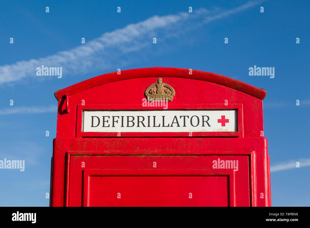 Una tradizionale cassetta telefonica pubblica di colore rosso brillante convertita per ospitare un defibrillatore di emergenza comunitario a Peppard Common, Oxfordshire Foto Stock