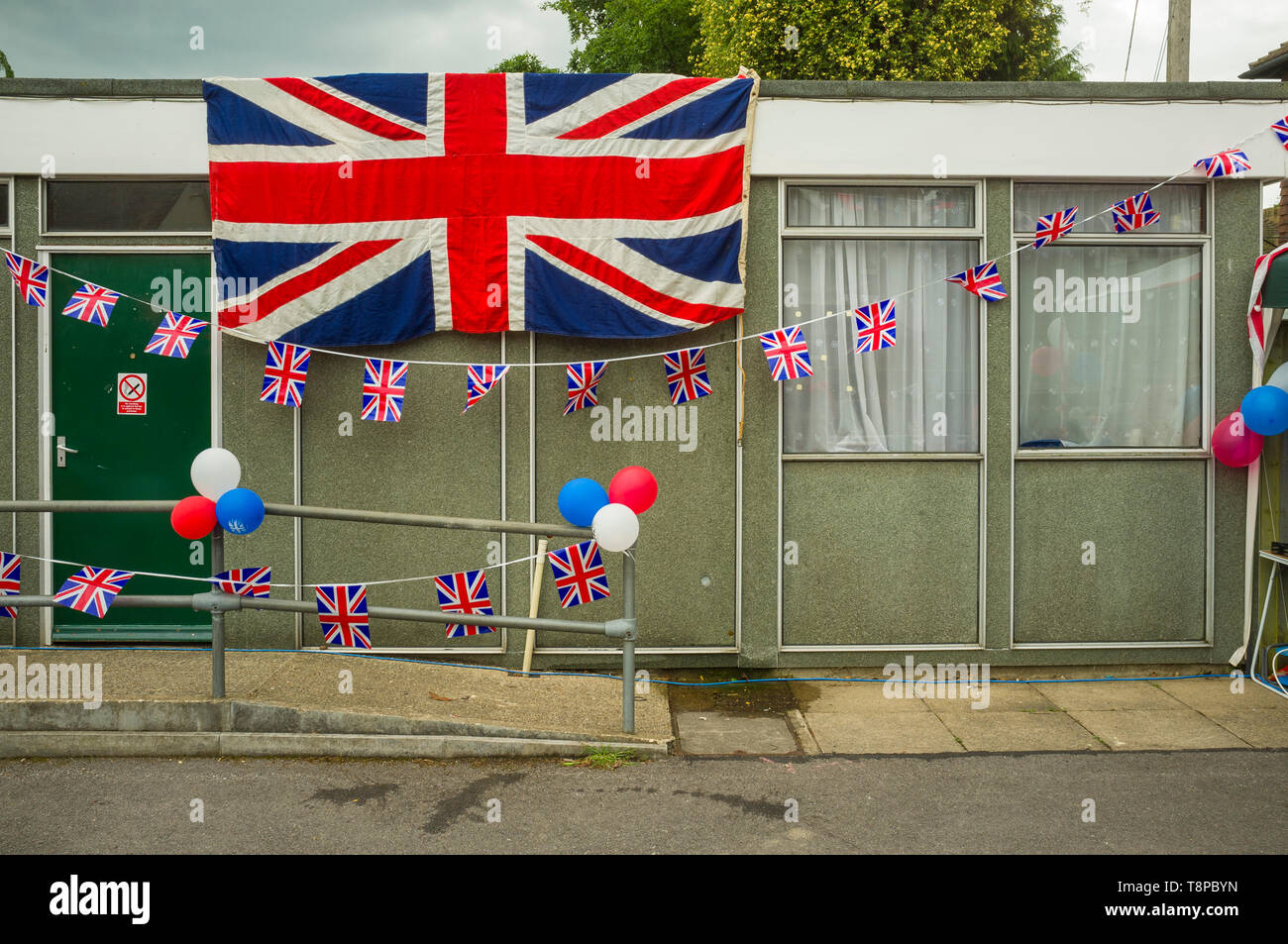 Union Jack bandiera e bunting decorano un edificio scolastico portatile temporaneo Drab in una festa di strada per celebrare il Giubileo dei diamanti della Regina Foto Stock