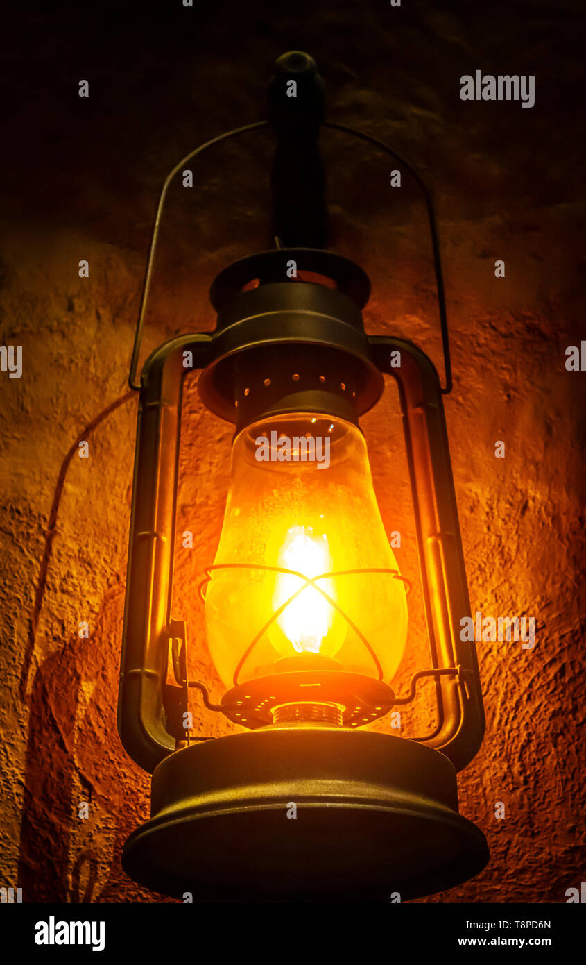 Una vecchia lampada di kerosene è appeso su una parete di argilla in una  stanza buia Foto stock - Alamy