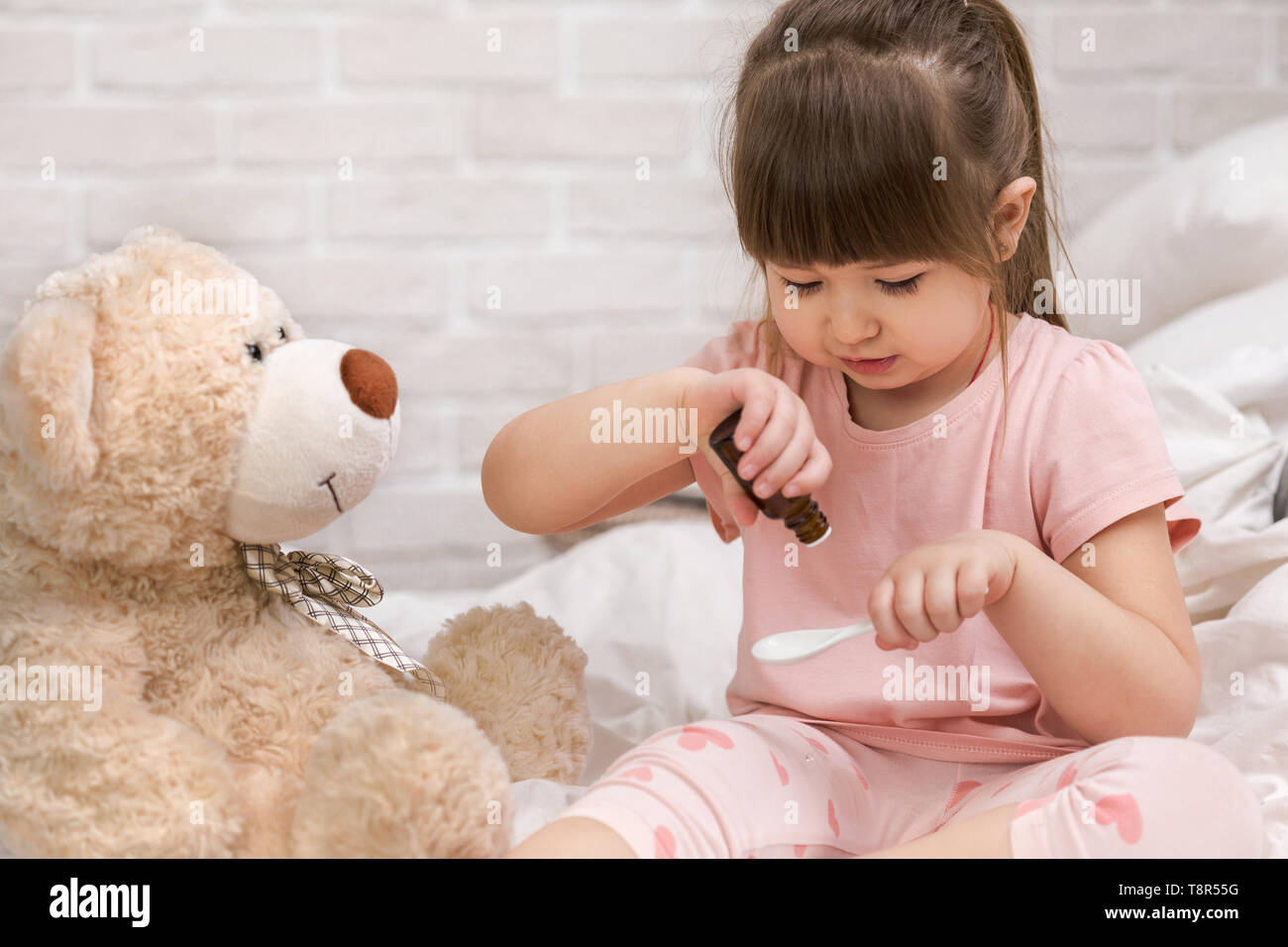 Carina ragazza bambino la riproduzione medico con Teddy bear a casa. Foto Stock