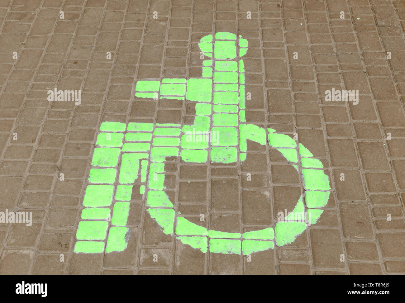 Lo spazio di parcheggio delle auto per disabili il segno disegnato sulla piastrella su strada. Foto Stock