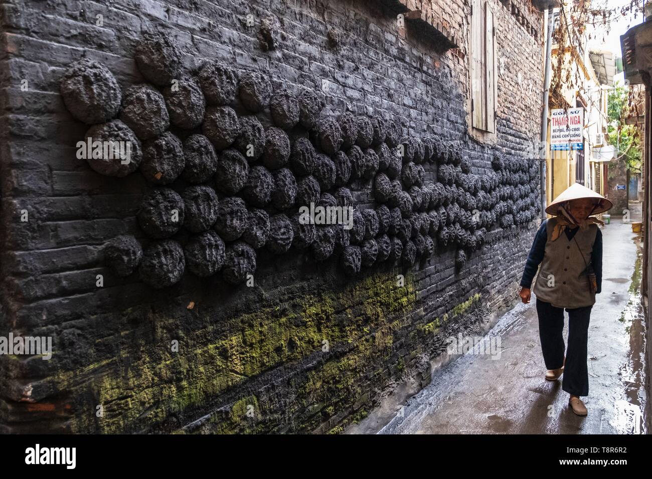 Il Vietnam, Bat Trang, vicino Hanoi, ceramista village, zolle di carbone bloccati su una parete di una casa tradizionale Foto Stock