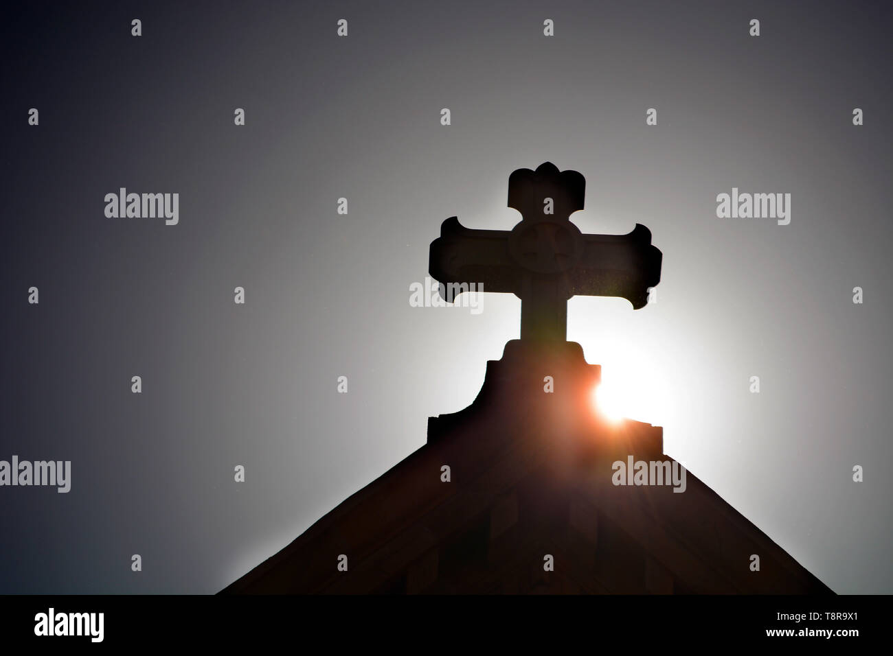 Il sole del mattino sorge dietro la croce in cima alla Basilica Cattedrale di San Francesco di Assisi a Santa Fe, New Mexico USA. Foto Stock