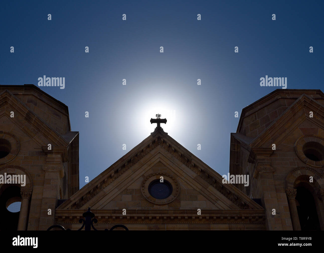 Il sole del mattino sorge dietro la croce in cima alla Basilica Cattedrale di San Francesco di Assisi a Santa Fe, New Mexico USA. Foto Stock