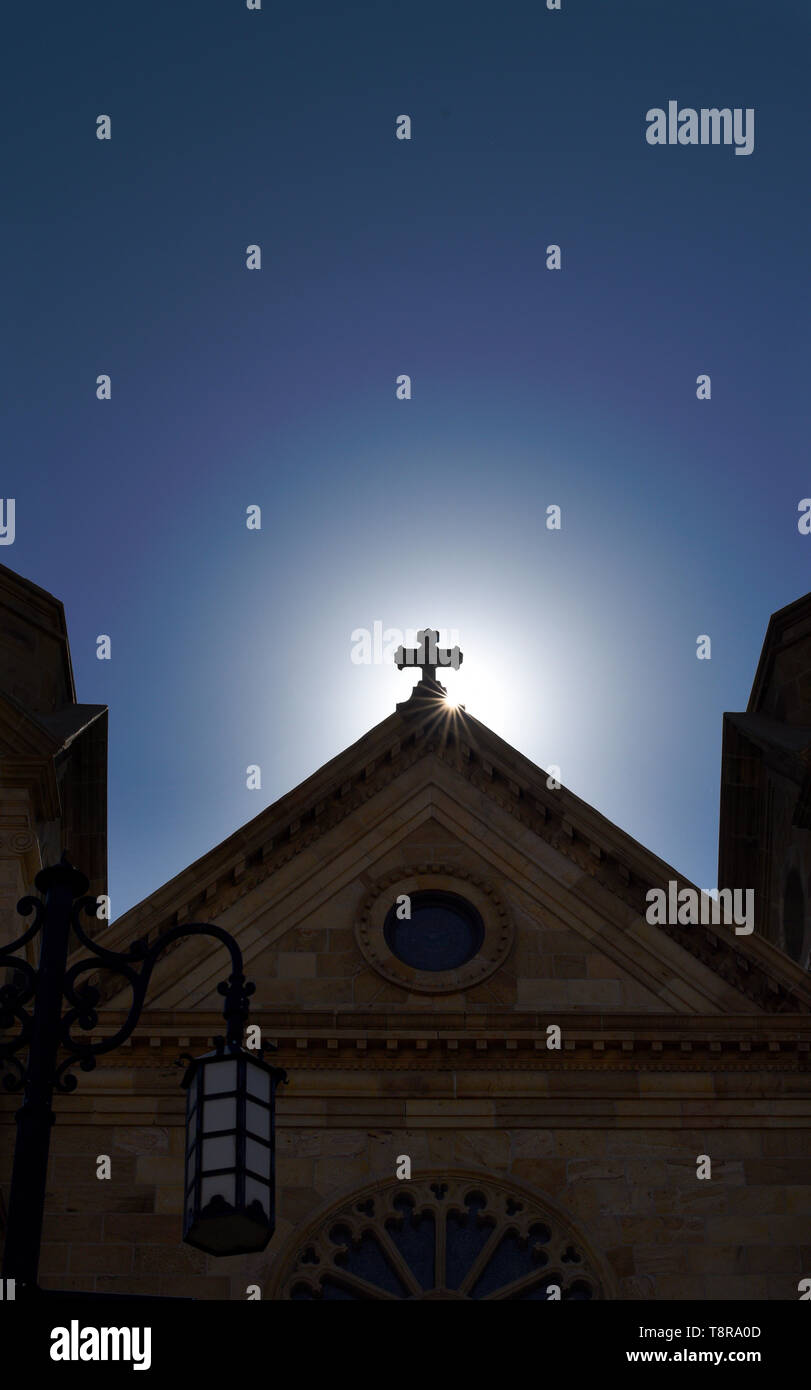 Il sole del mattino sorge dietro la croce in cima alla Basilica Cattedrale di San Francesco di Assisi a Santa Fe, New Mexico USA. Foto Stock