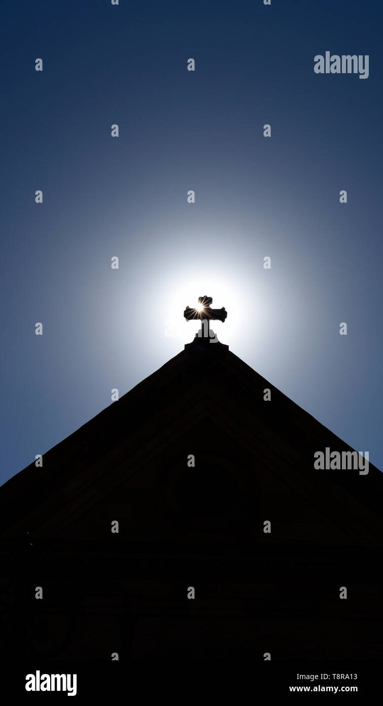 Il sole del mattino sorge dietro la croce in cima alla Basilica Cattedrale di San Francesco di Assisi a Santa Fe, New Mexico USA. Foto Stock