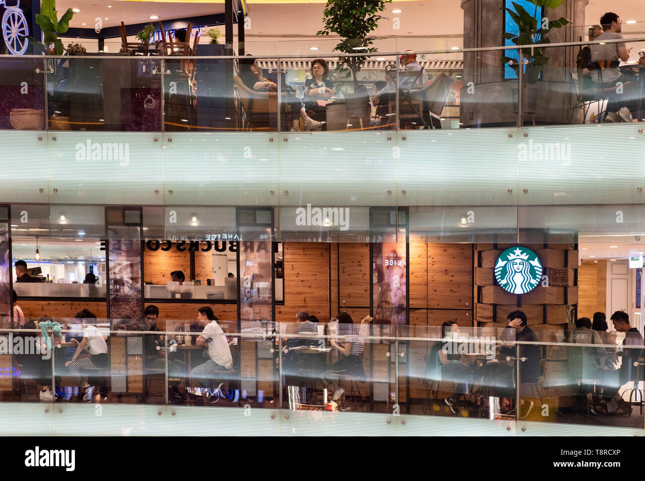 I clienti si vede a bere caffè presso la multinazionale americana la catena Starbucks Coffee ristorante a Hong Kong shopping mall. Foto Stock