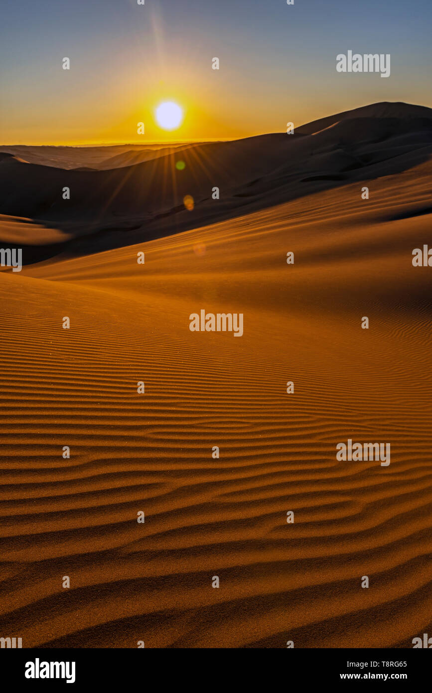 Infinito tramonto con bella sabbia increspature e lens flare, incontaminata costiera deserto del Perù tra Ica e Huacachina, Sud America. Foto Stock