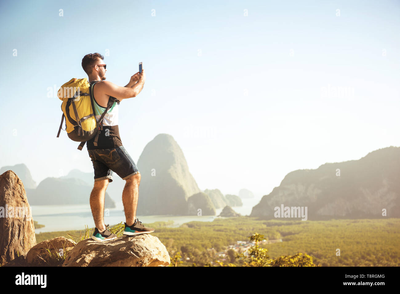 Backpacker tourist sorge su big rock e prende mobile photo a Viewpoint Foto Stock