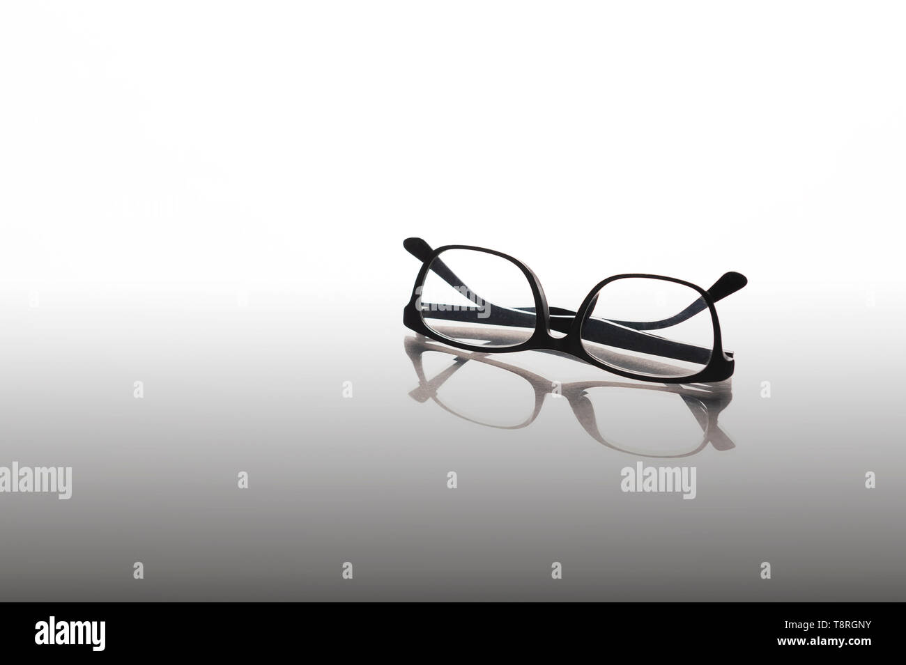 Telaio nero occhiali su sfondo a specchio, lettura,rilassante o rompere il concetto. Foto Stock