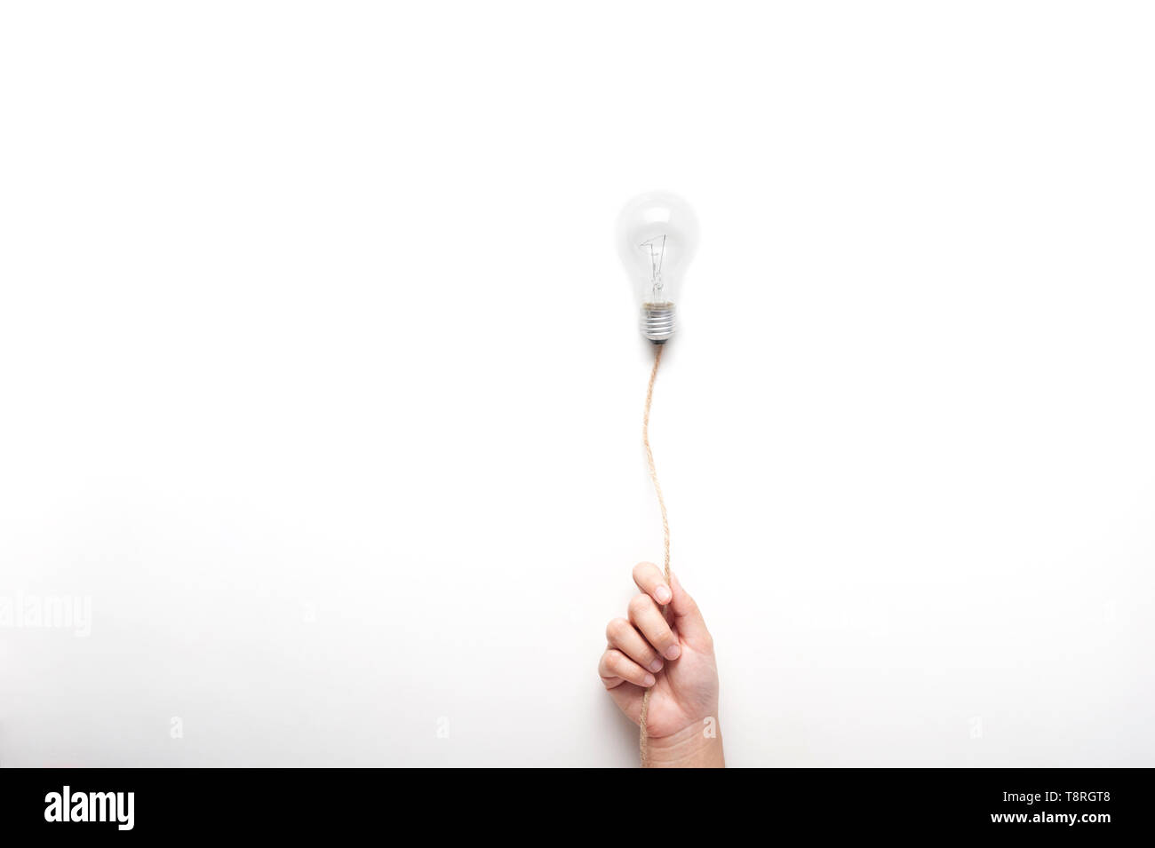 Mano che tiene la lampadina luce sulla corda galleggiante su sfondo bianco con texting spazio idea, concetto. Foto Stock