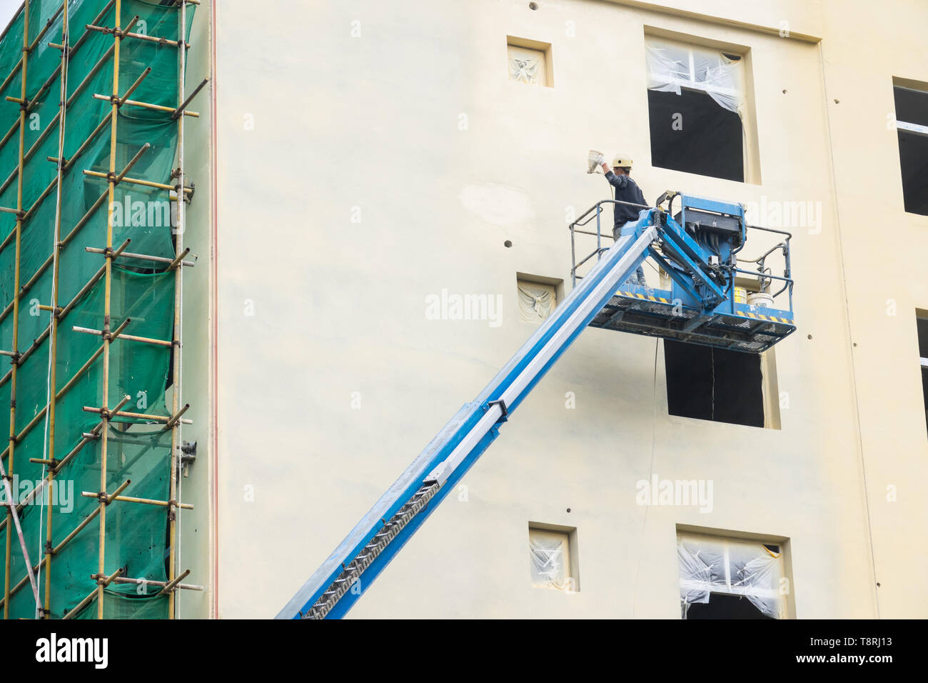 Un uomo di lavoro edificio dipinto da aerografo su gru in sito in costruzione Foto Stock