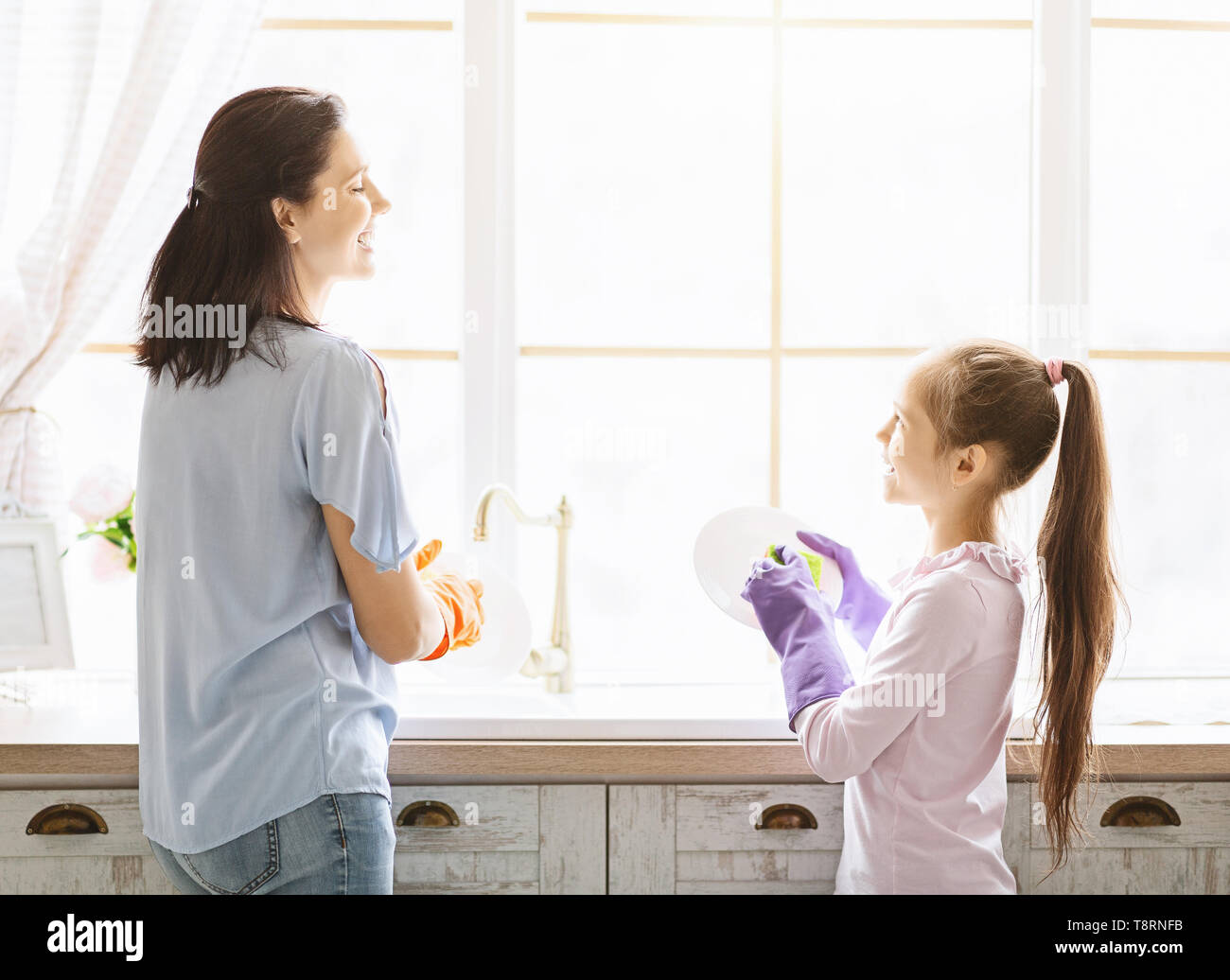 Figlia aiutando la mamma a lavare i piatti in cucina Foto Stock