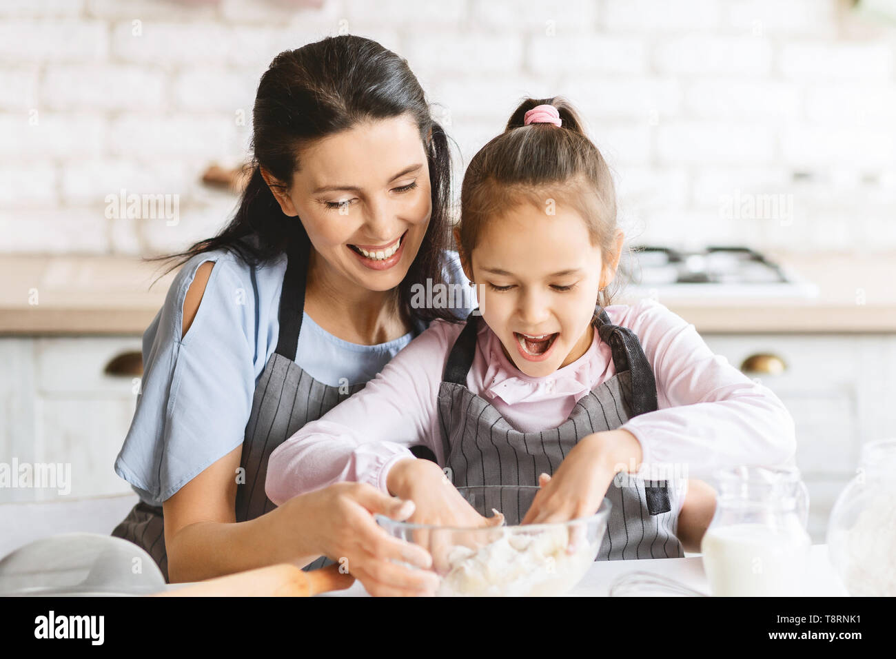 Ragazza carina godersi il tempo con MOM, impastare la pasta per torta Foto Stock