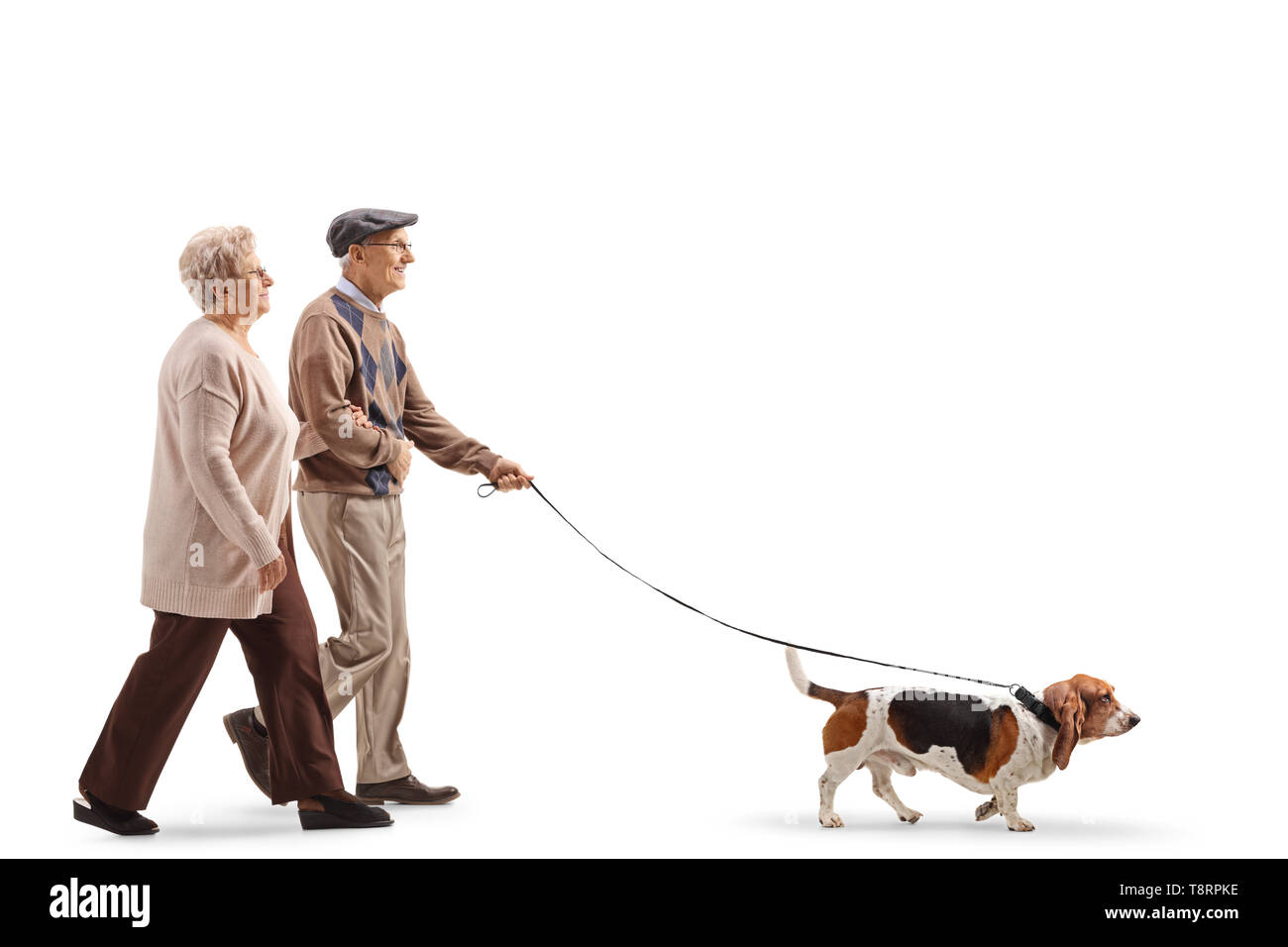 Lunghezza piena ripresa di profilo di una coppia senior a piedi una basset hound dog isolati su sfondo bianco Foto Stock