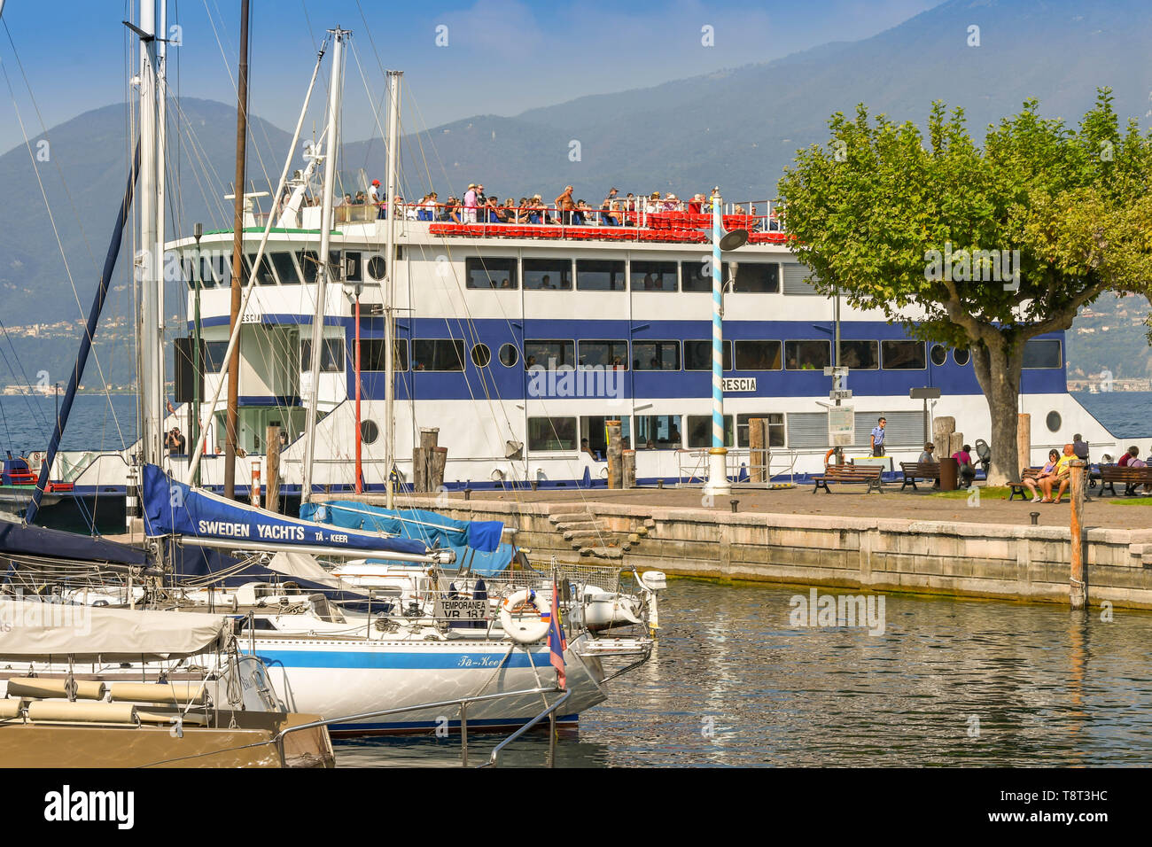 TORRI DEL BENACO SUL LAGO DI GARDA, Italia - Settembre 2018: barche a vela nel porto della città di Torri del Benaco sul Lago di Garda. Un traghetto passeggeri è Foto Stock
