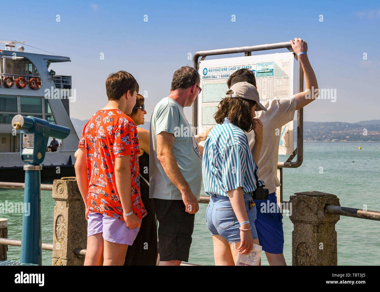 SIRMIONE SUL LAGO DI GARDA, Italia - Settembre 2018: i membri della famiglia controllare l'orario traghetti al porto a Sirmione sul Lago di Garda. Foto Stock