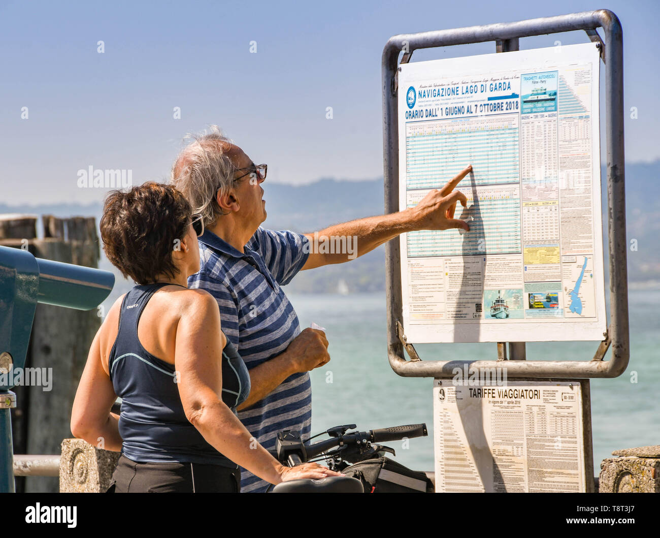 SIRMIONE SUL LAGO DI GARDA, Italia - Settembre 2018: uomo e donna controllare l'orario traghetti al porto a Sirmione sul Lago di Garda. Foto Stock