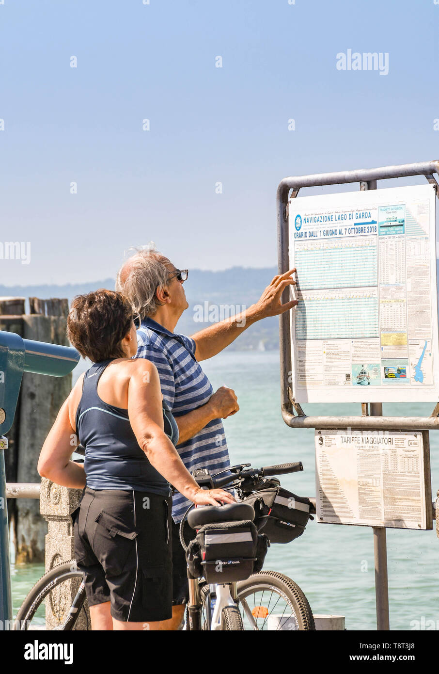 SIRMIONE SUL LAGO DI GARDA, Italia - Settembre 2018: uomo e donna controllare l'orario traghetti al porto a Sirmione sul Lago di Garda. Foto Stock