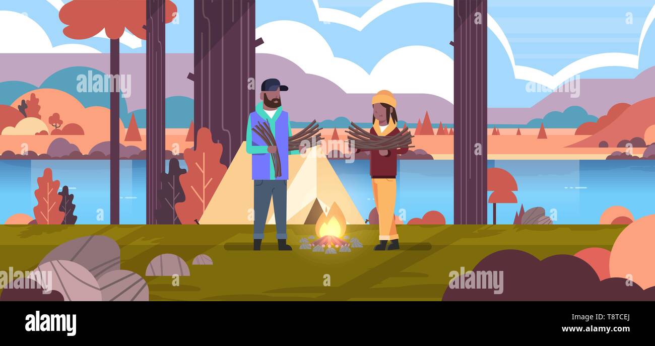 Giovane turista escursionisti holding di legna da ardere african american uomo donna organizzando fire n camp tenda escursionismo camping concetto autunno paesaggio naturale del fiume Illustrazione Vettoriale