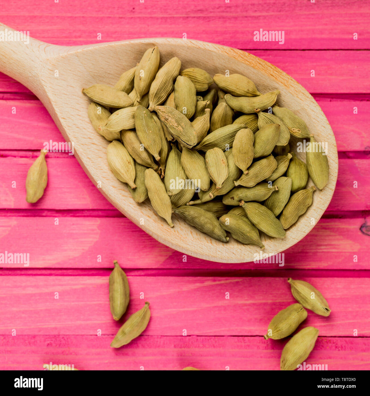 Cucchiaio di legno pieno di speziato indiano i semi di cardamomo Foto Stock