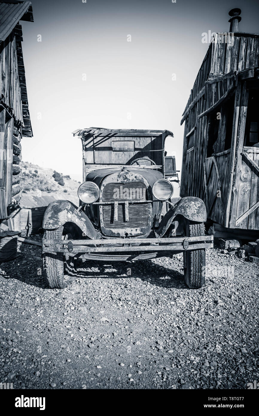 Un vecchio 1920-30s era Ford auto parcheggiata tra due case rustiche. Foto Stock