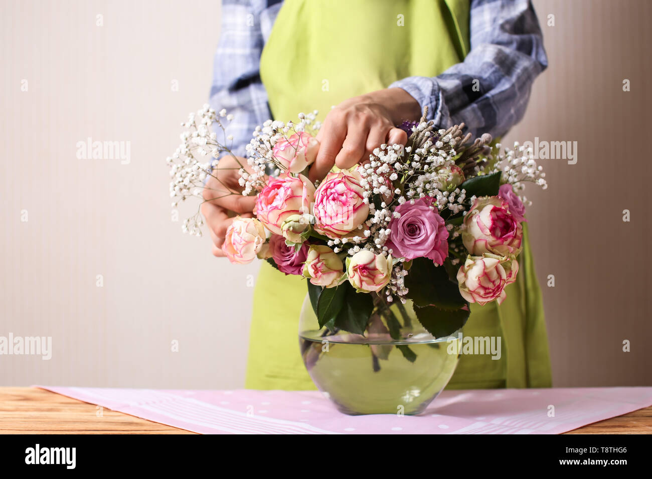 Fioraio rendendo bouquet di fiori belli al tavolo di legno Foto Stock