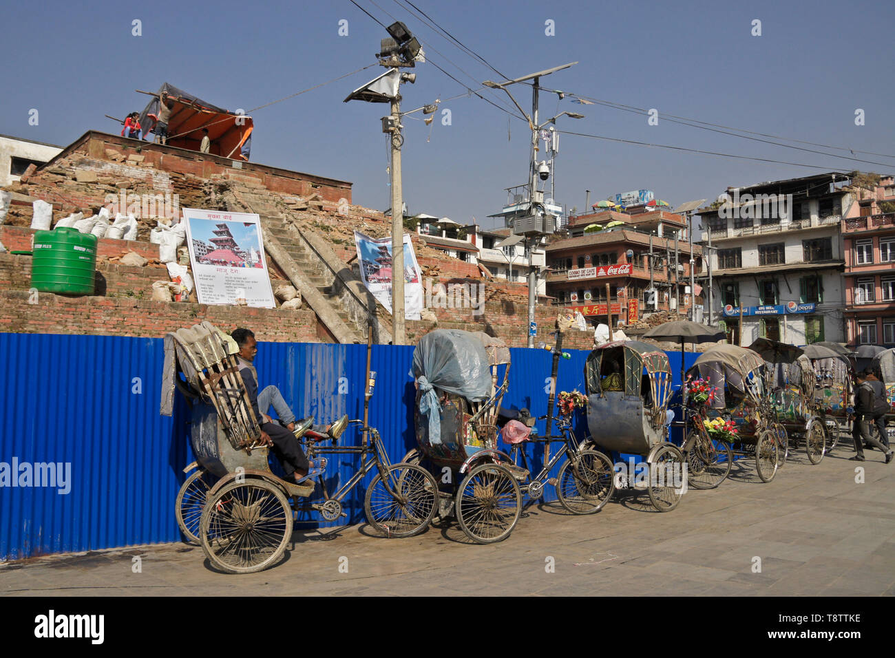 Pedicabs attendono i clienti vicino al restauro di Maju Dewal, distrutto nel 2015 Terremoto, Durbar Square, Kathmandu, Nepal Foto Stock