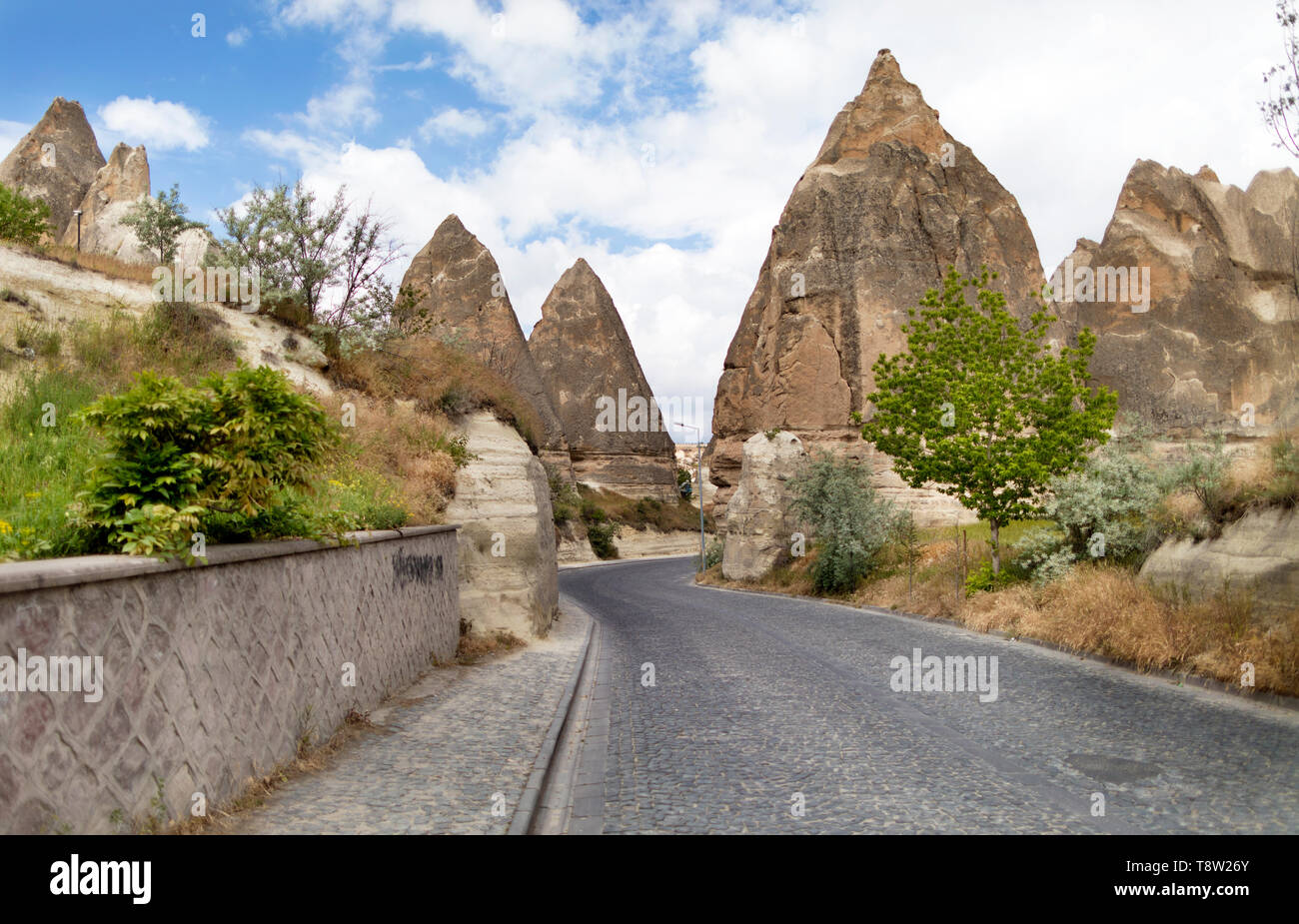 Una strada tortuosa da pietre per pavimentazione passa in prossimità del cono di pietra case in antiche rocce di Goreme, Kappadoki. Paesaggio rurale in modo rurale di LIF Foto Stock