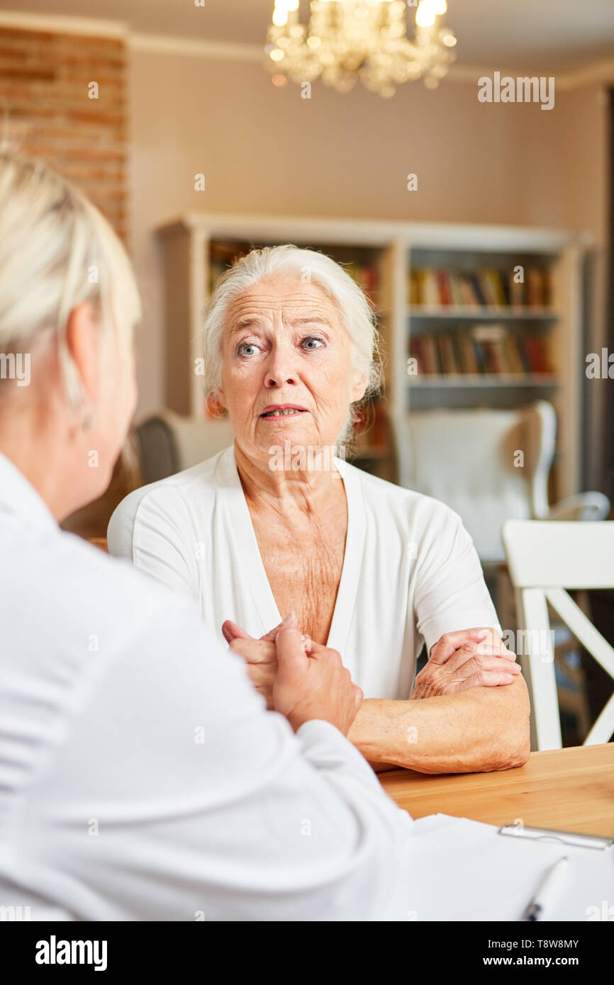 Medico si prende cura degli anziani come un paziente in consultazione o home visita Foto Stock