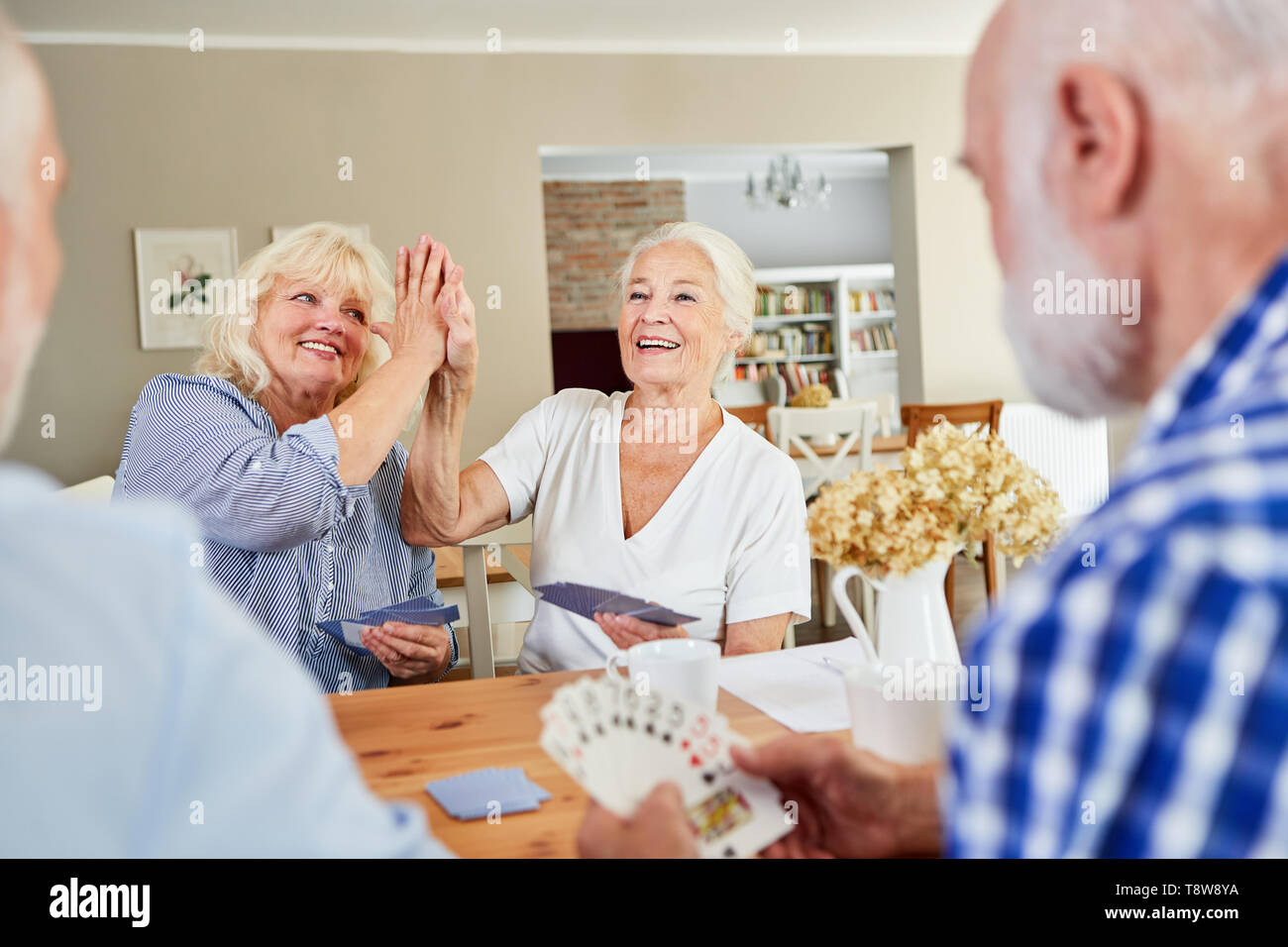 Due donne senior di godere di giocare a carte con gli amici Foto Stock