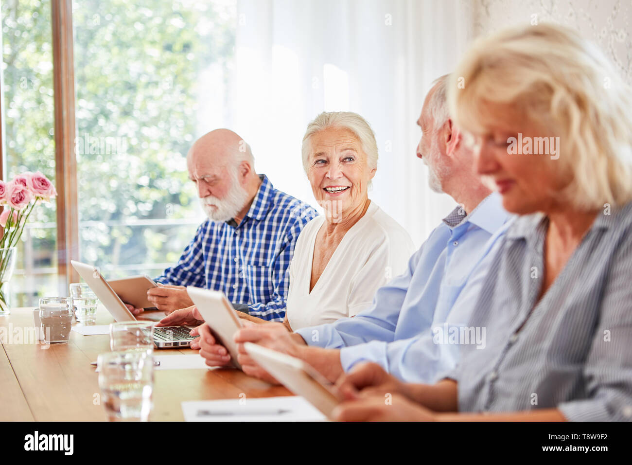 Gruppo di anziani in casa di riposo è l'apprendimento in classe computer con tavoletta e il computer portatile Foto Stock