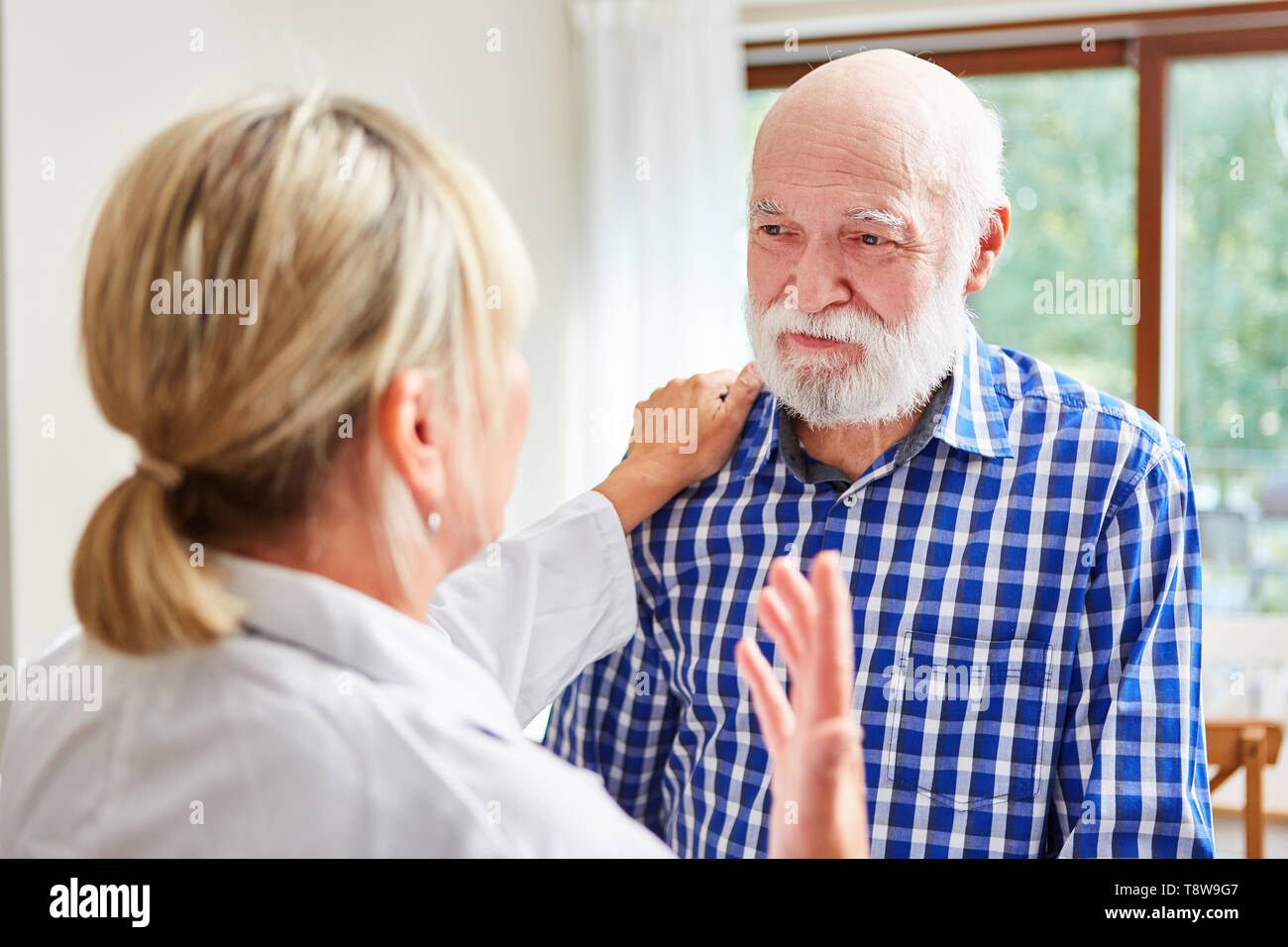 La donna come un medico di famiglia comfort di un uomo anziano con demenza in consultazione Foto Stock