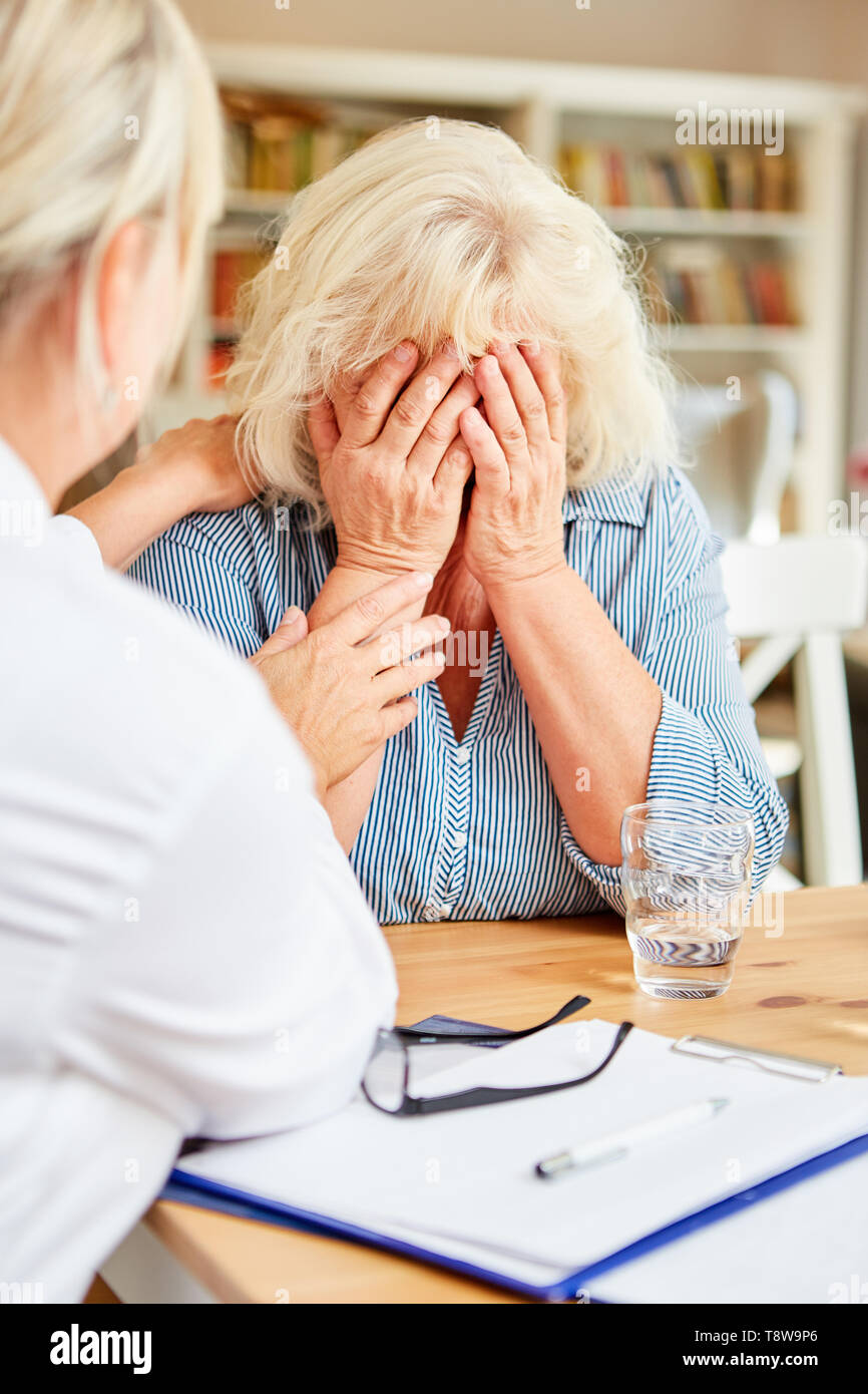 Il pianto del vecchio paziente è confortata da un medico sensibile durante una visita a casa Foto Stock