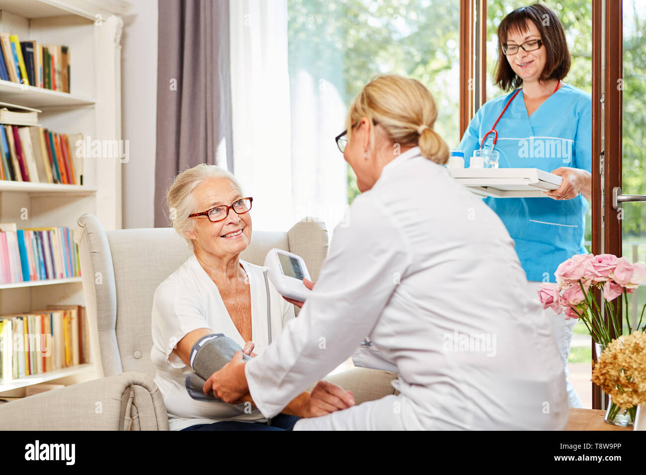 L'infermiera misura la pressione del sangue di un senior in condizioni di vita assistita Foto Stock
