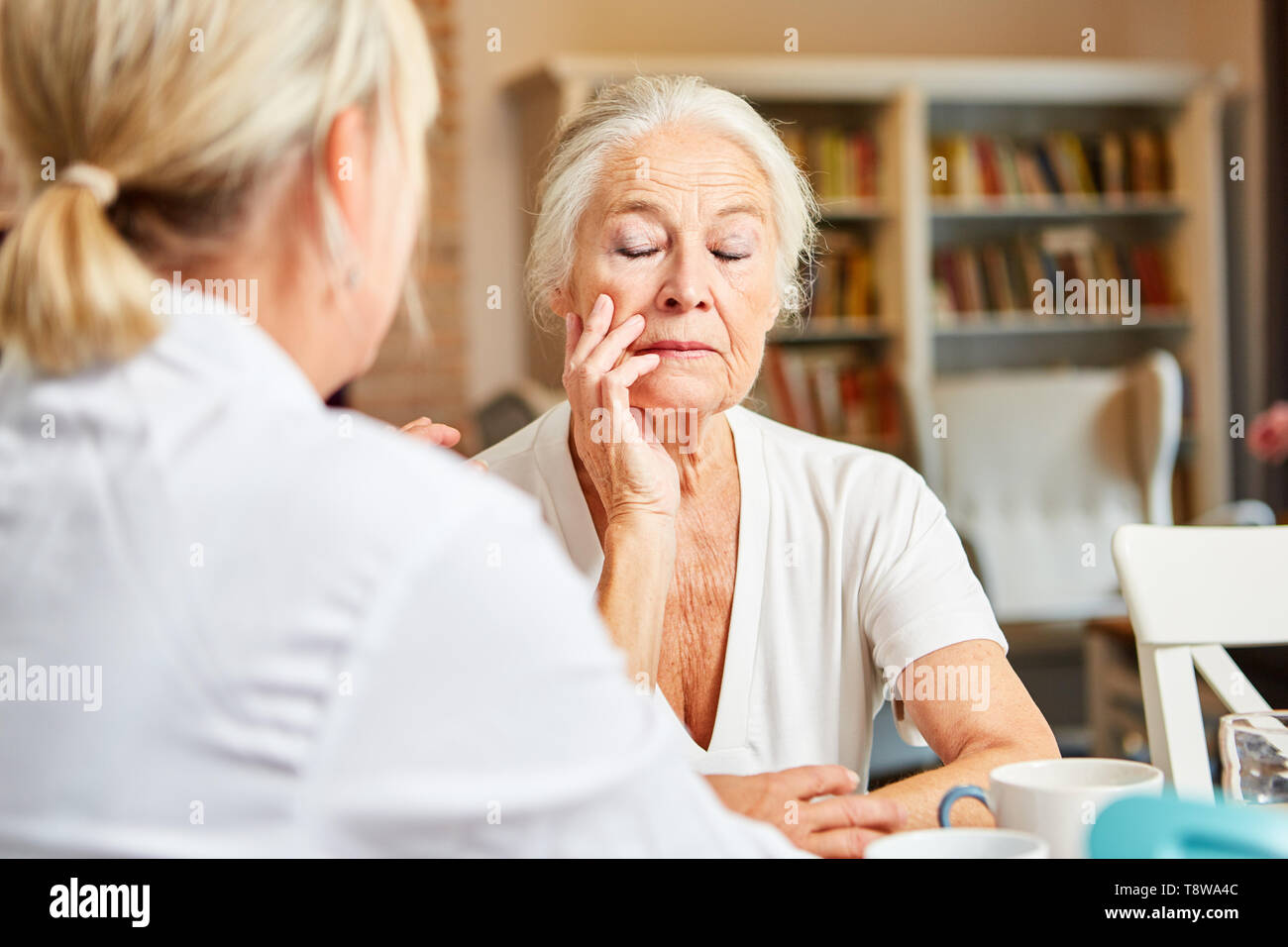 Medico o terapista guarda dopo la donna anziana con depressione durante una visita a casa Foto Stock