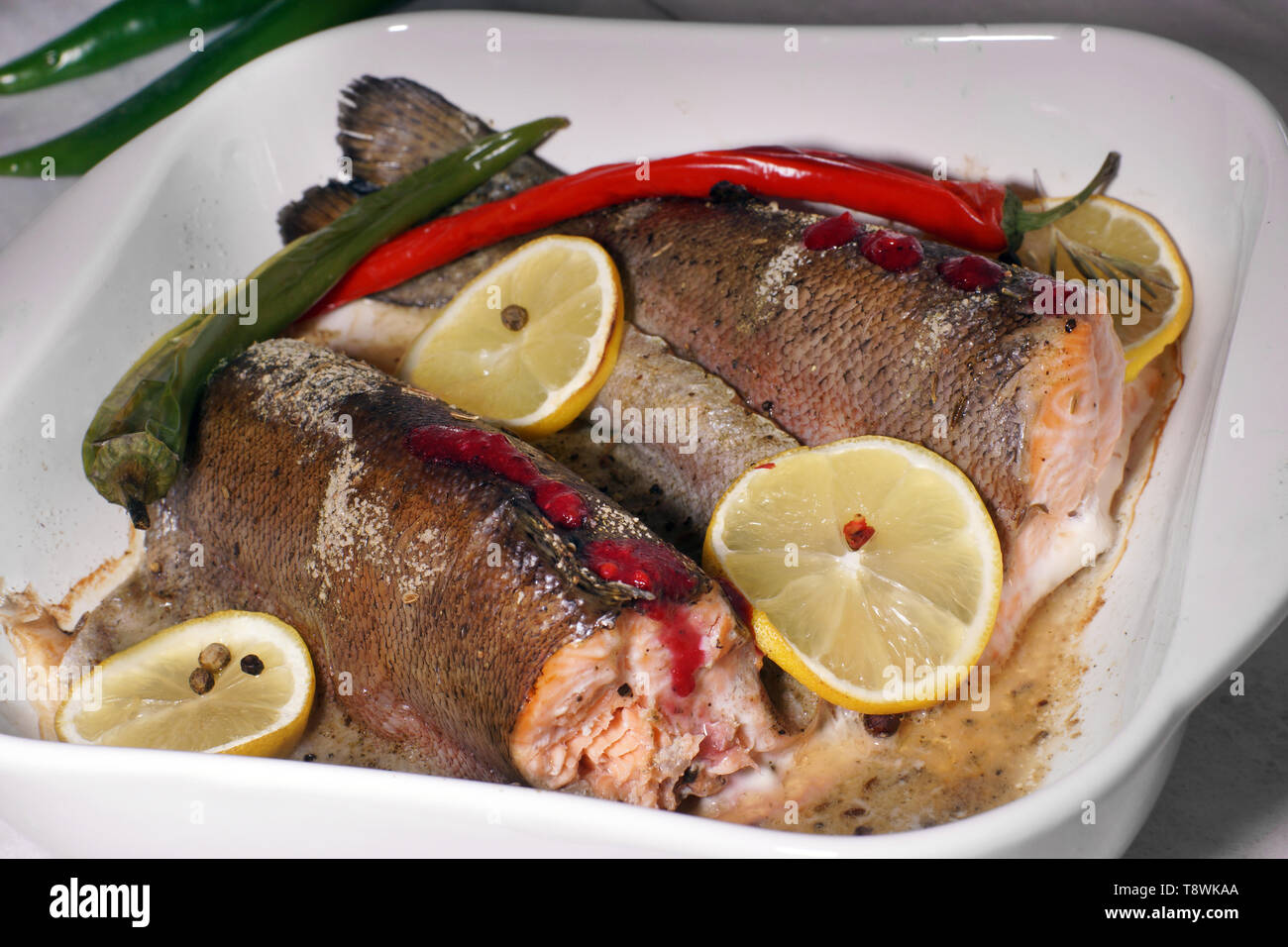 Trota di rosso pesce cotto al forno con limone e pepe caldo in un bianco resistente al calore piatto. Foto Stock