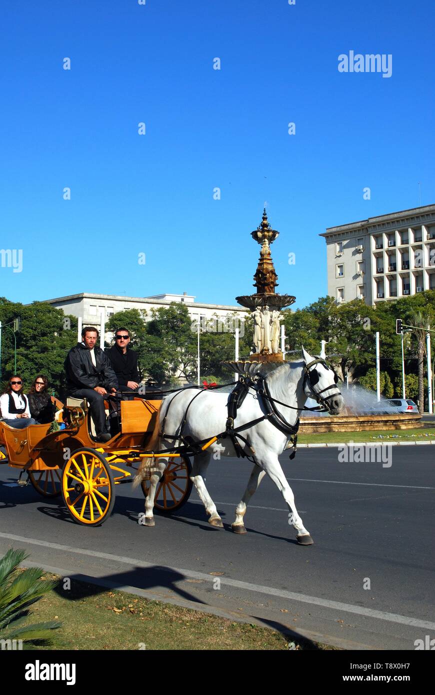 I turisti facendo un giro in un carro trainato da cavalli nella Plaza Don Juan de Austria con una fontana per la parte posteriore, Siviglia, Spagna. Foto Stock