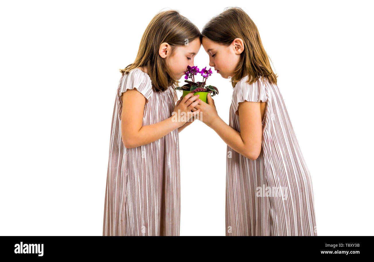 Gemello ragazza sono profumati fiori viola pot verde. Bambine che i bambini sono in lutto con gli occhi chiusi. Concetto di dolore la perdita dei loro cari. Foto Stock