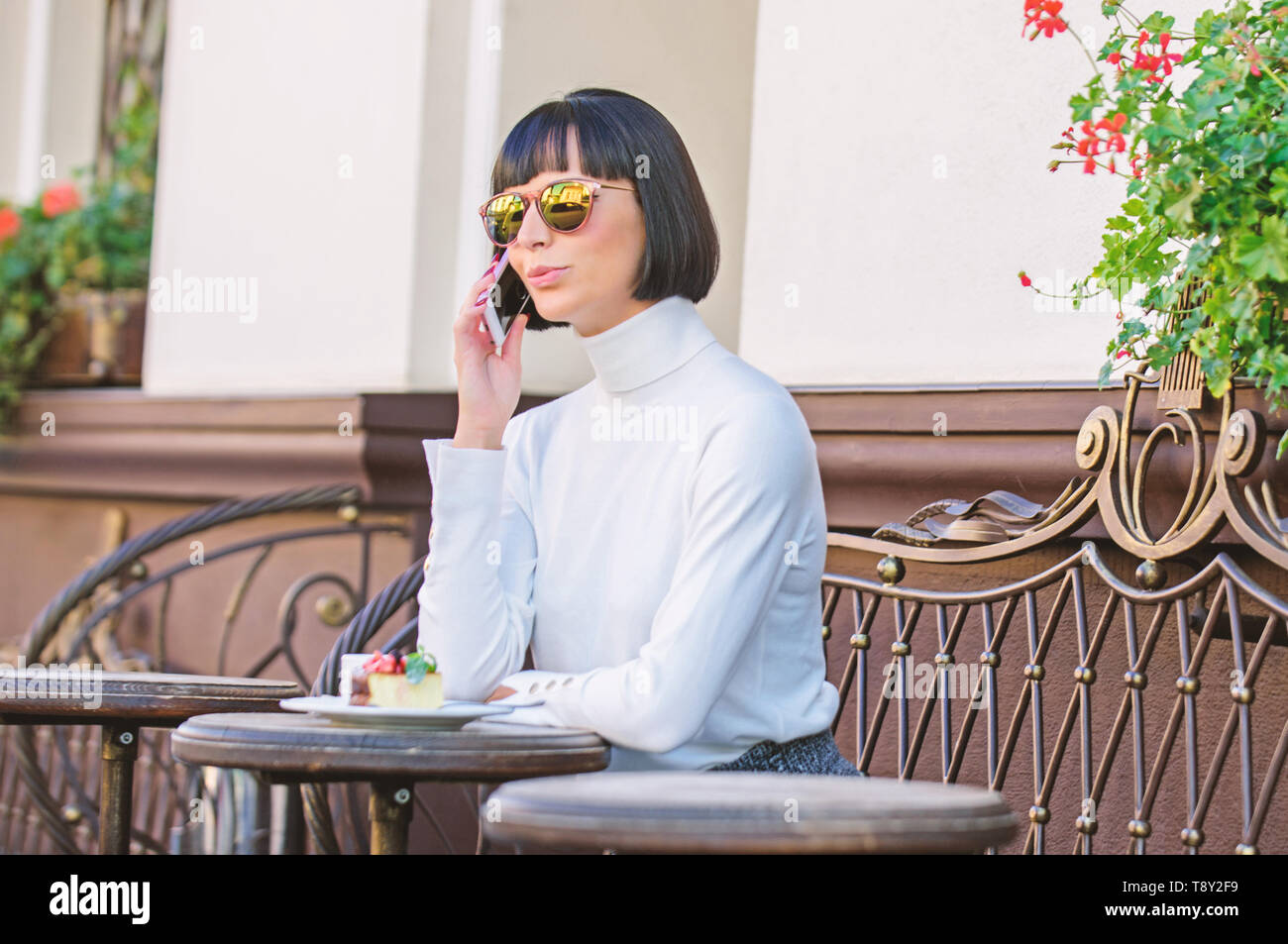 Chiamare amico. Ragazza signora alla moda con lo smartphone. Concetto di piacere. Donna elegante attraente brunette trascorrere tempo libero bar terrazza sfondo. Piacevole il tempo e il tempo libero. Relax e coffee break. Foto Stock