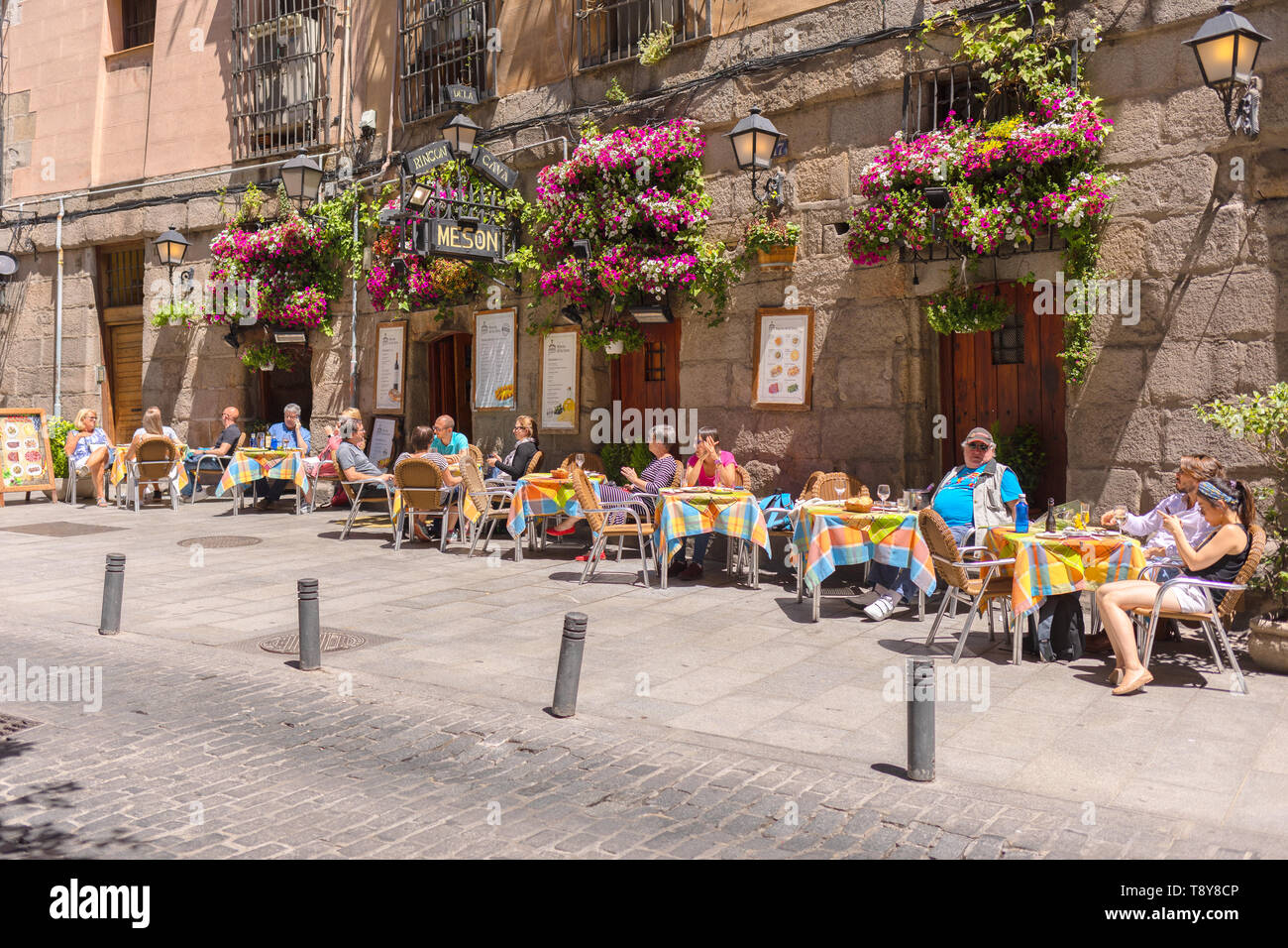 Vecchia strada accogliente a Madrid con un piccolo ristorante e turisti che si godono il pranzo Foto Stock