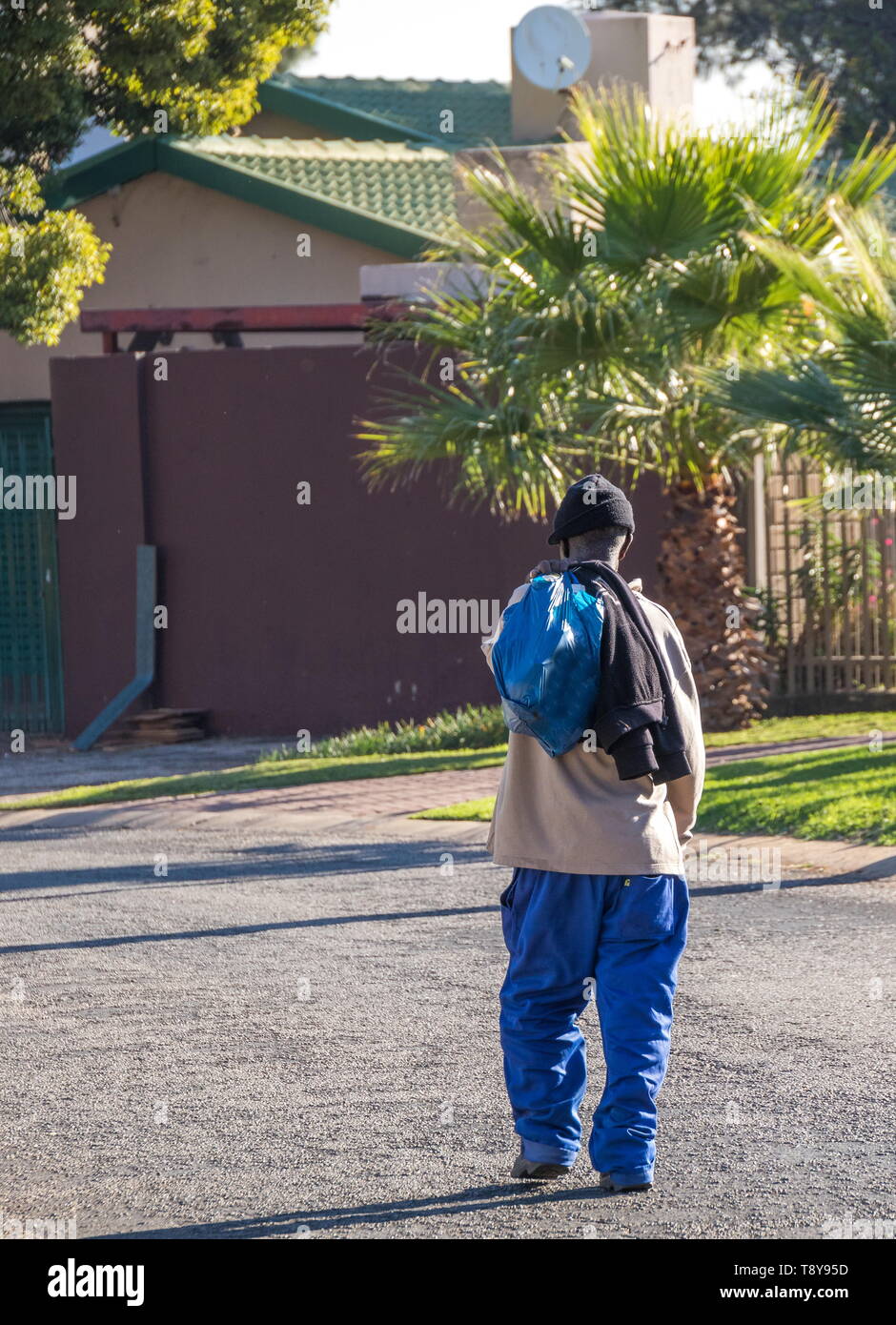 Johannesburg, Sud Africa - anziani non identificato uomo nero passeggiate in casa nel pomeriggio dopo una giornata di lavoro nella città immagine in formato verticale Foto Stock